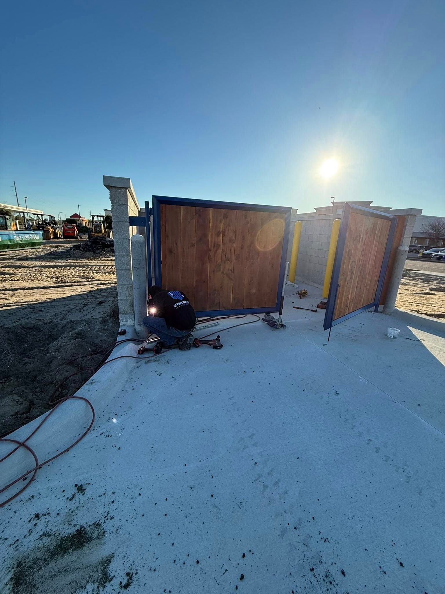 Construction site with wooden panels and concrete pillars under a bright sun.