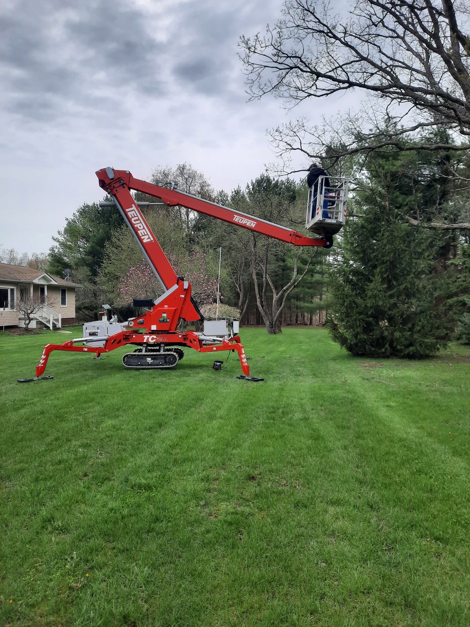 A red crane is sitting in the middle of a lush green field.