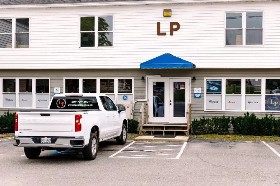 A white truck is parked in front of a building that says lp.