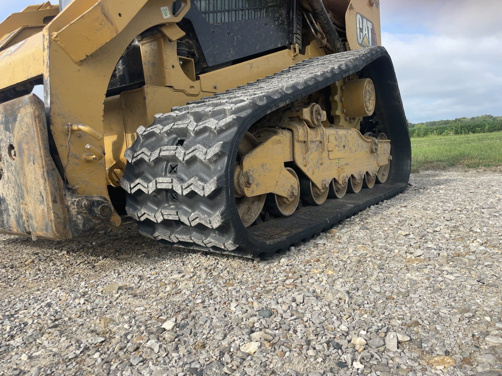 Yellow tracked construction machine on gravel, shown from the side outdoors.
