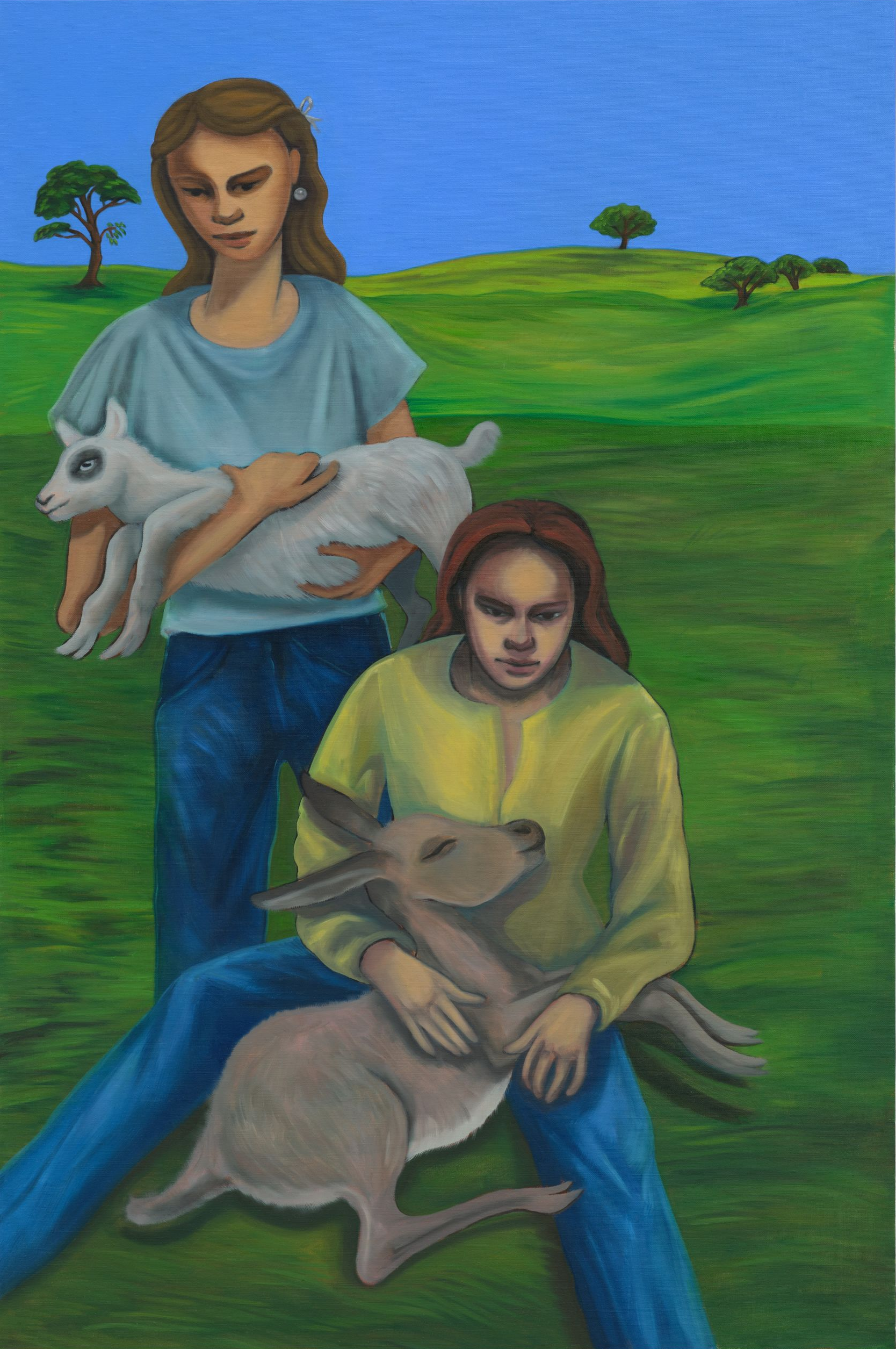Two women in a grassy field hold small animals. One woman holds a white goat; the other, a tan deer.