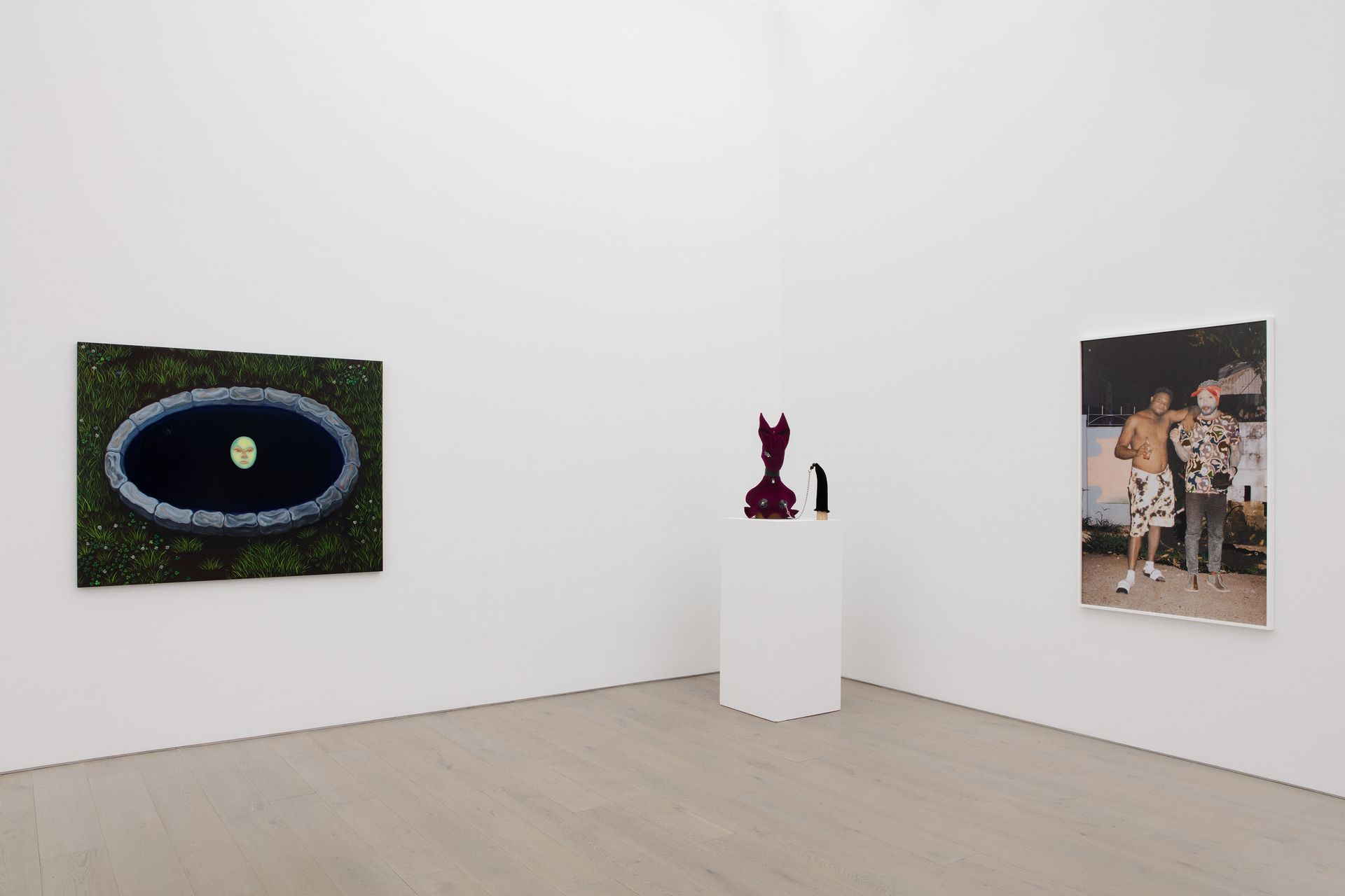 Gallery view with three artworks: a pool, a sculpture, and a photo of people, all in a white room.
