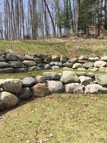 Un tas de rochers posés au sommet d’une colline herbeuse.