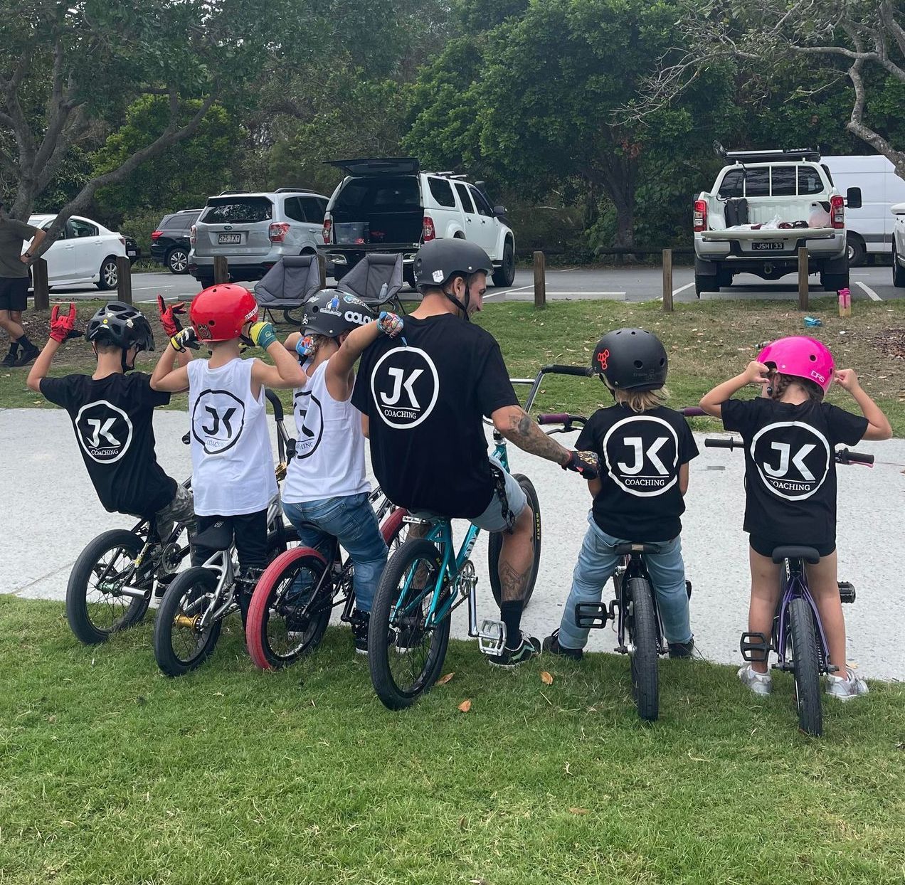 A group of children are riding bicycles with the letter k on their shirts
