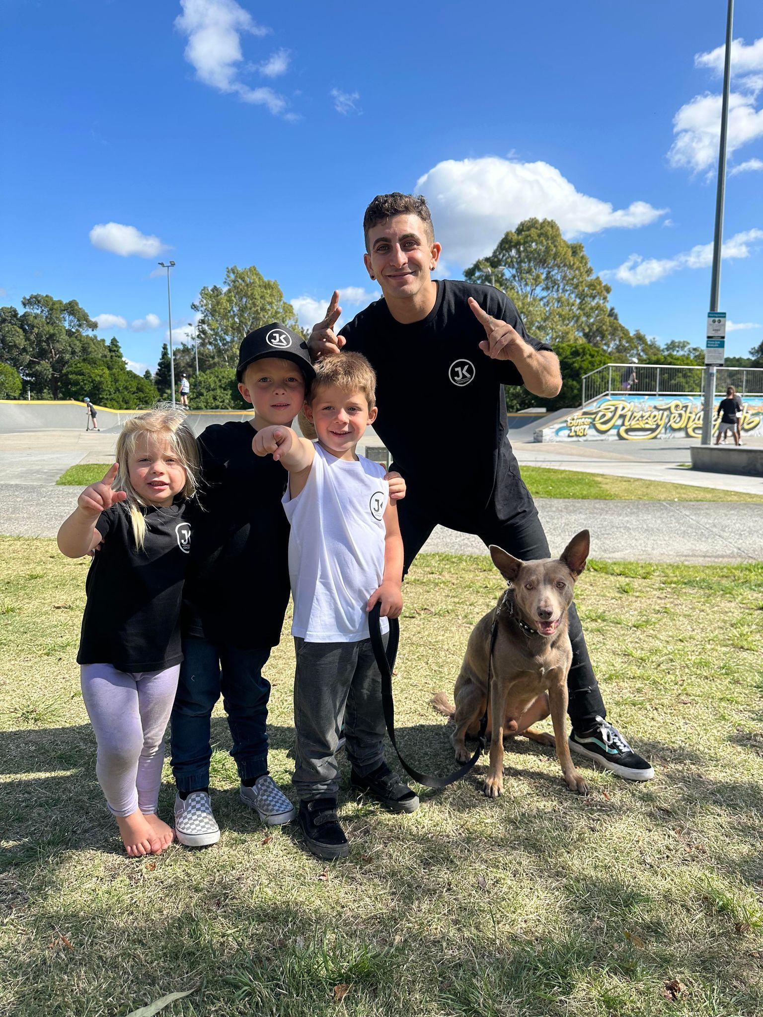 A man and three children are posing for a picture with a dog.