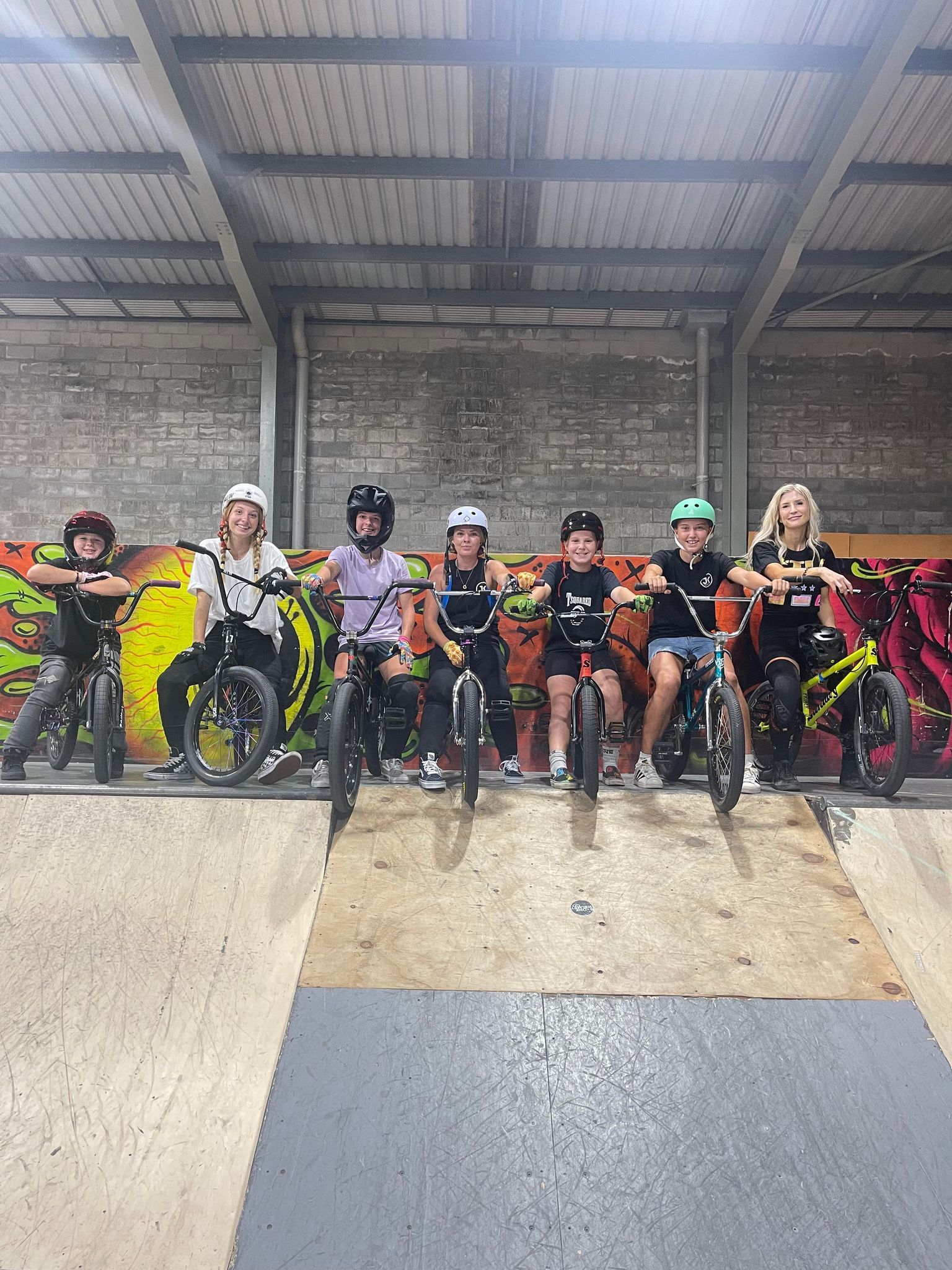 A group of children are riding bikes in a skate park.