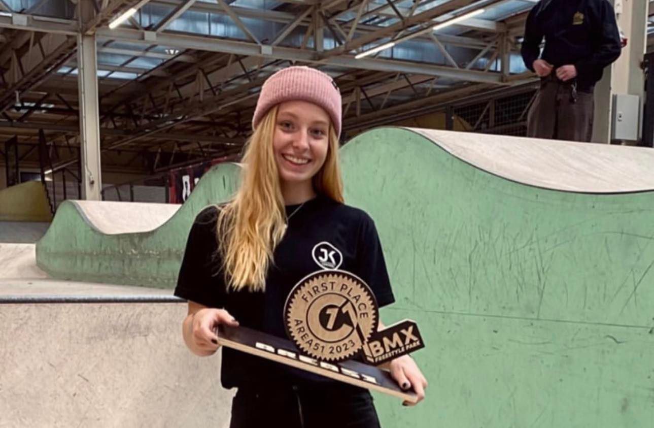 A young girl is holding a skateboard in a skate park.