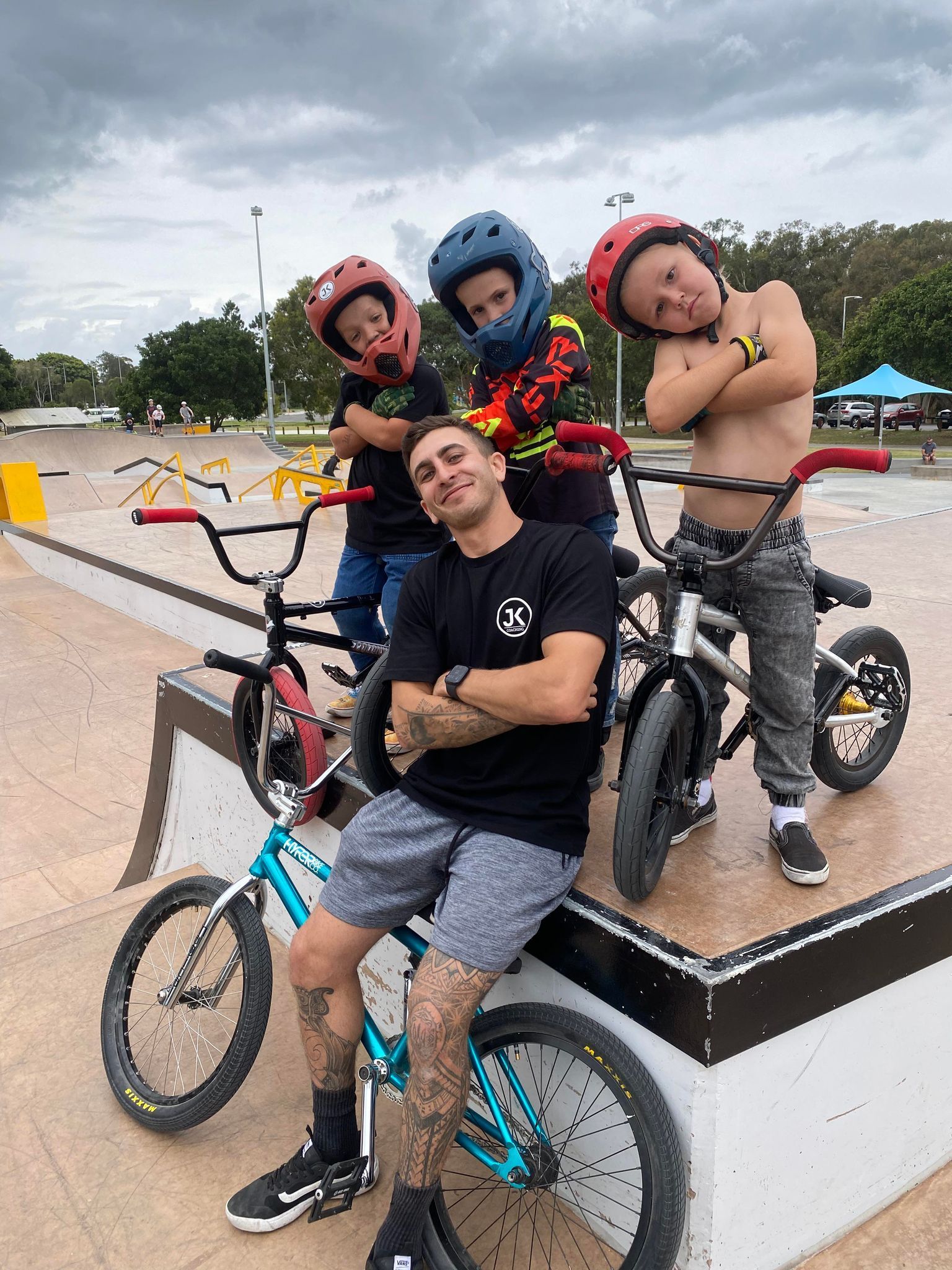 A man is sitting on a bike next to three children on bikes.