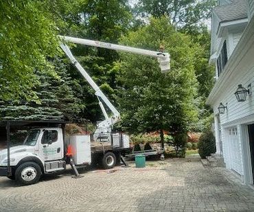 A white truck with a crane on top of it is parked in front of a house.