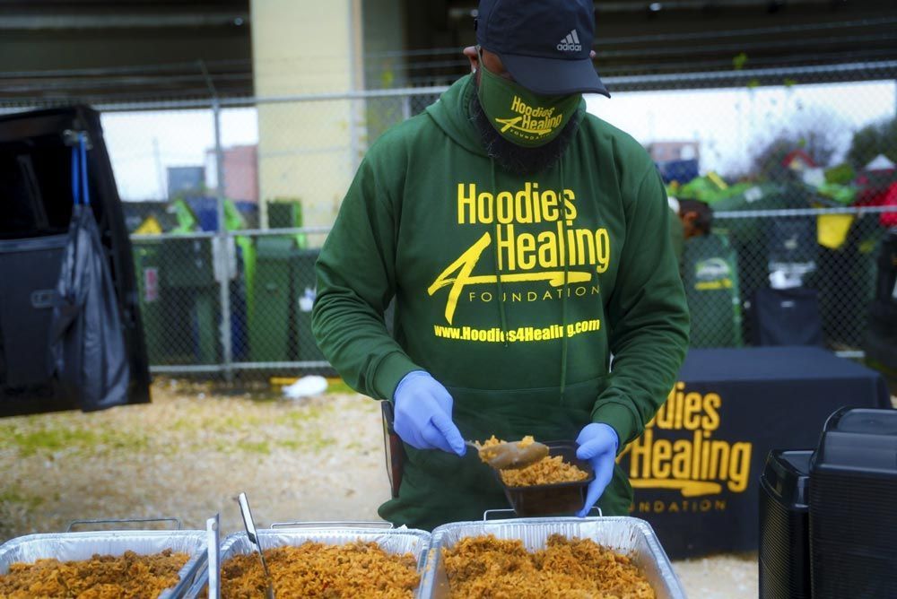 A man wearing a green hoodie and a hat is preparing food.