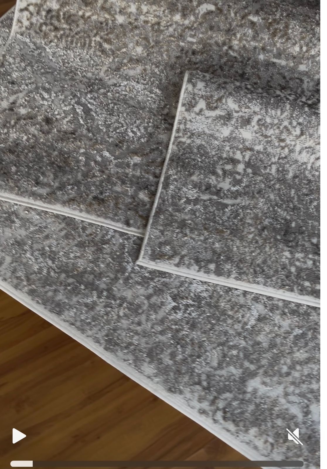 Alfombra estampada en tonos marrones y blancos con base de madera y jarrón de cristal encima.