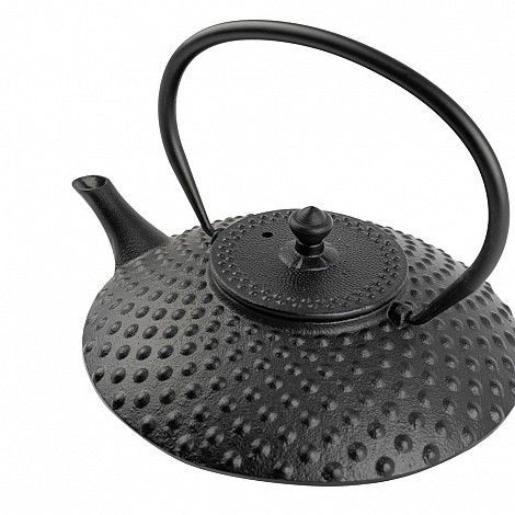 Tetera de hierro fundido negro con superficie tachonada, pico y asa sobre fondo blanco.