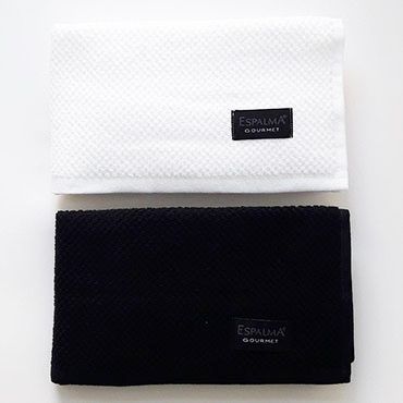 Dos paños de cocina doblados, uno color crema y otro gris, con la etiqueta 