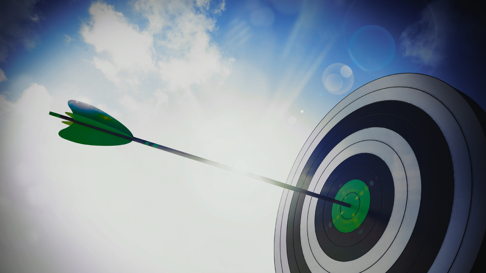 An arrow with green fletching strikes the center of a target against a bright, sunlit sky.