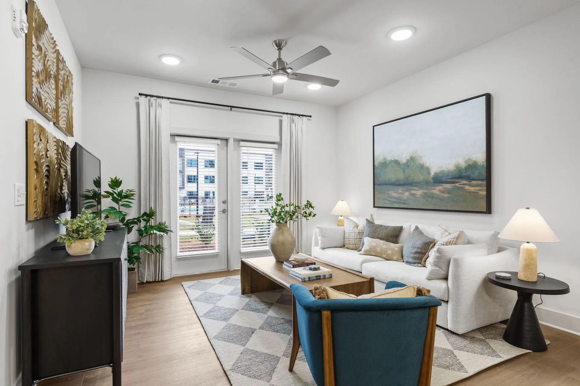 Living room with white walls, a sofa, and artwork, with a door leading to a balcony.