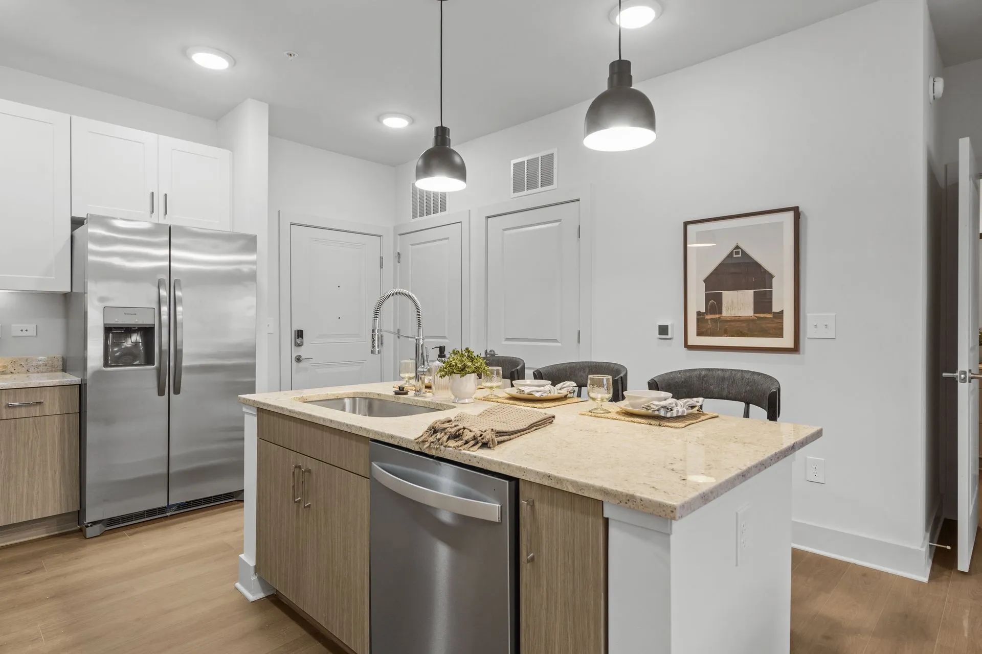 Modern kitchen with island, stainless steel appliances, and light wood cabinets.