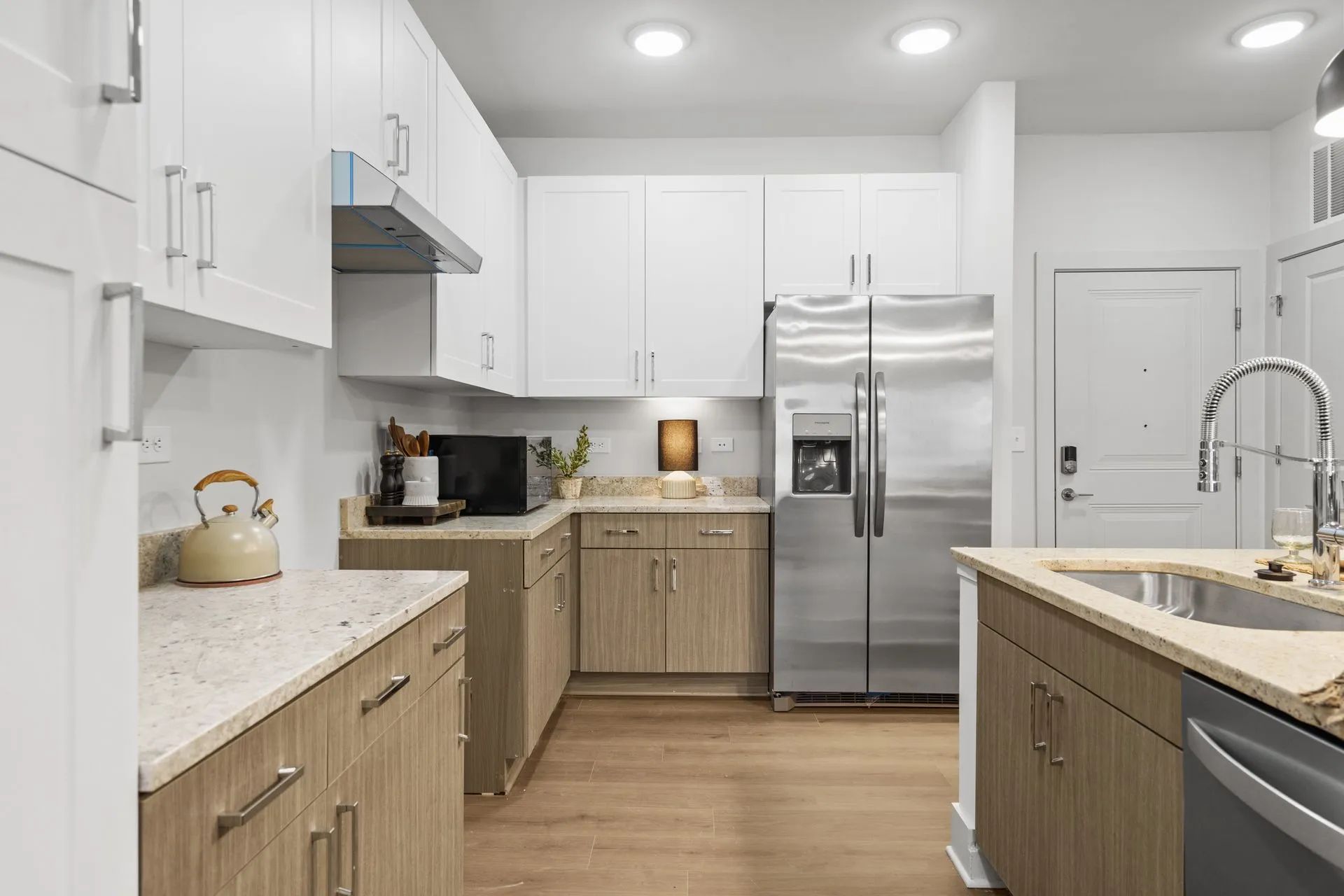 Kitchen with white and wood cabinets, stainless steel appliances, and beige countertops.