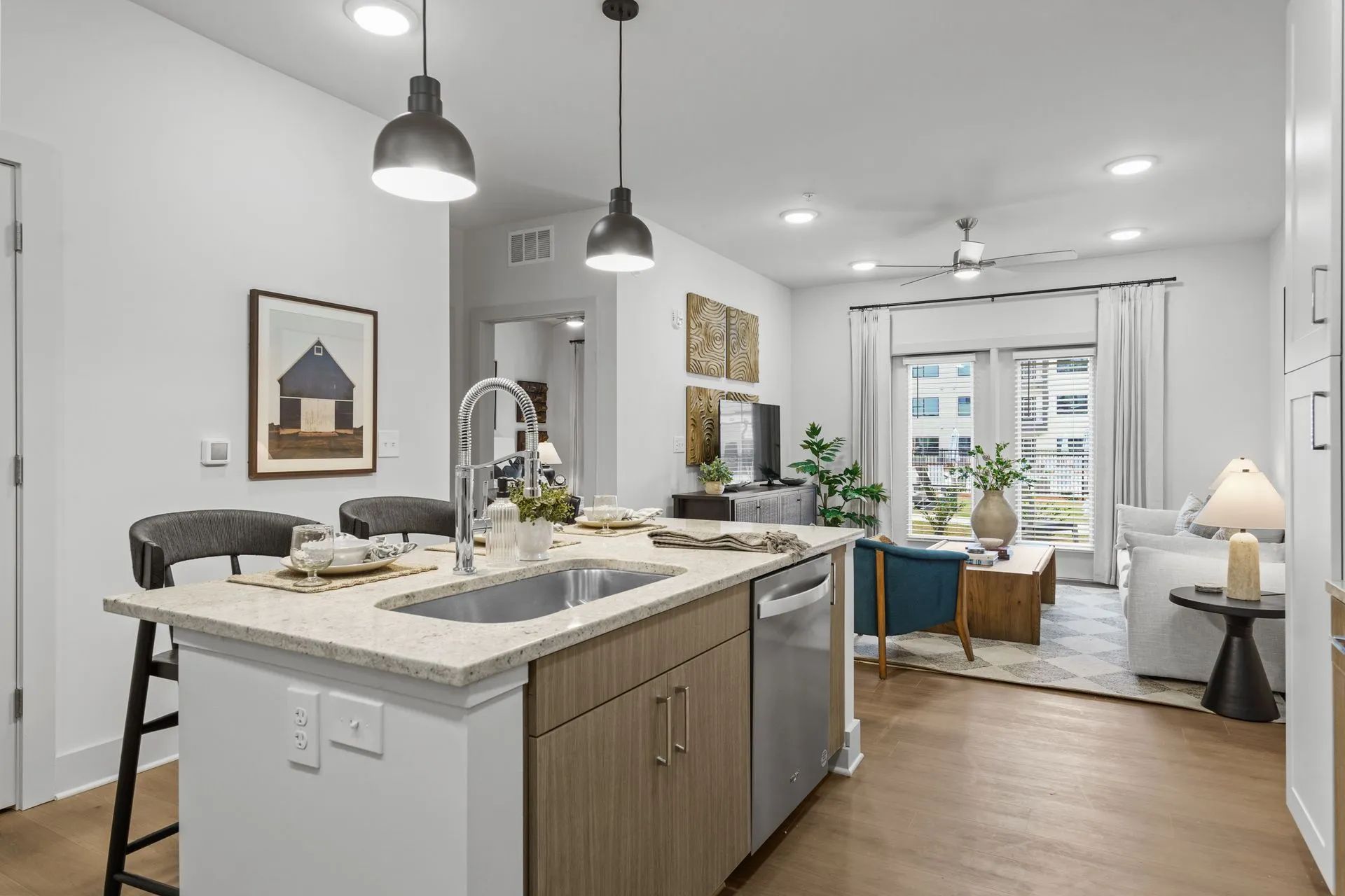 Modern kitchen with island, adjacent living area, overhead lights.