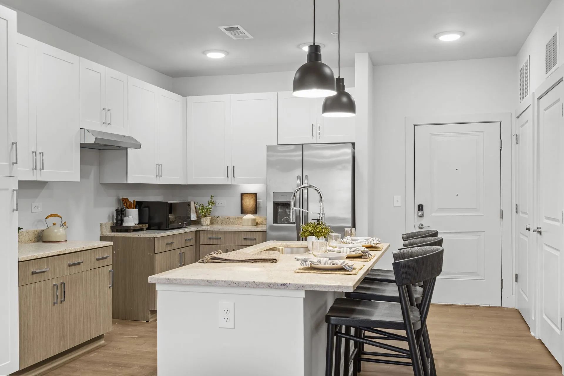 Modern kitchen with white cabinets, stainless steel appliances, and an island with stools.