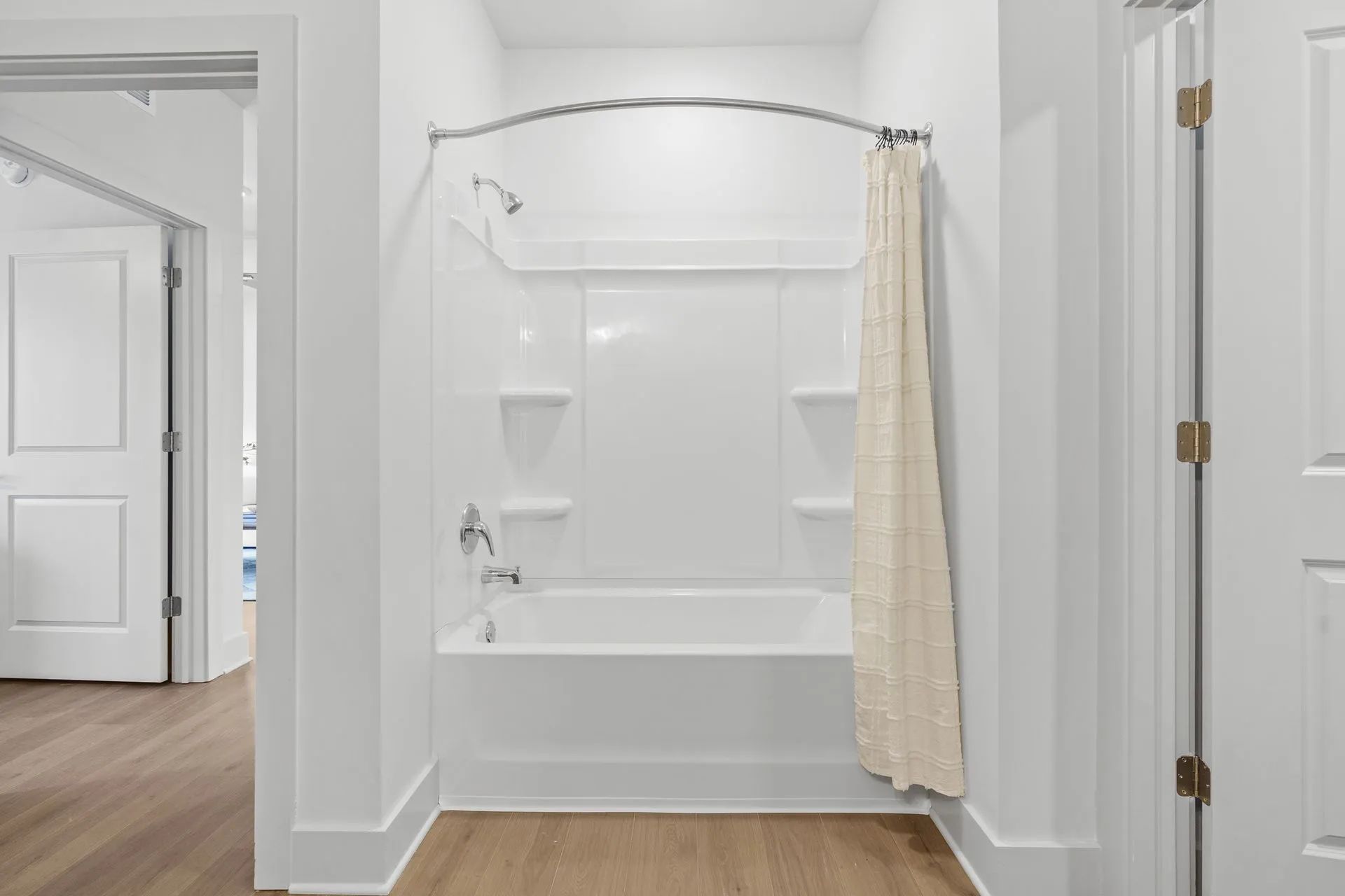White bathroom with a tub, shower, and tan shower curtain.
