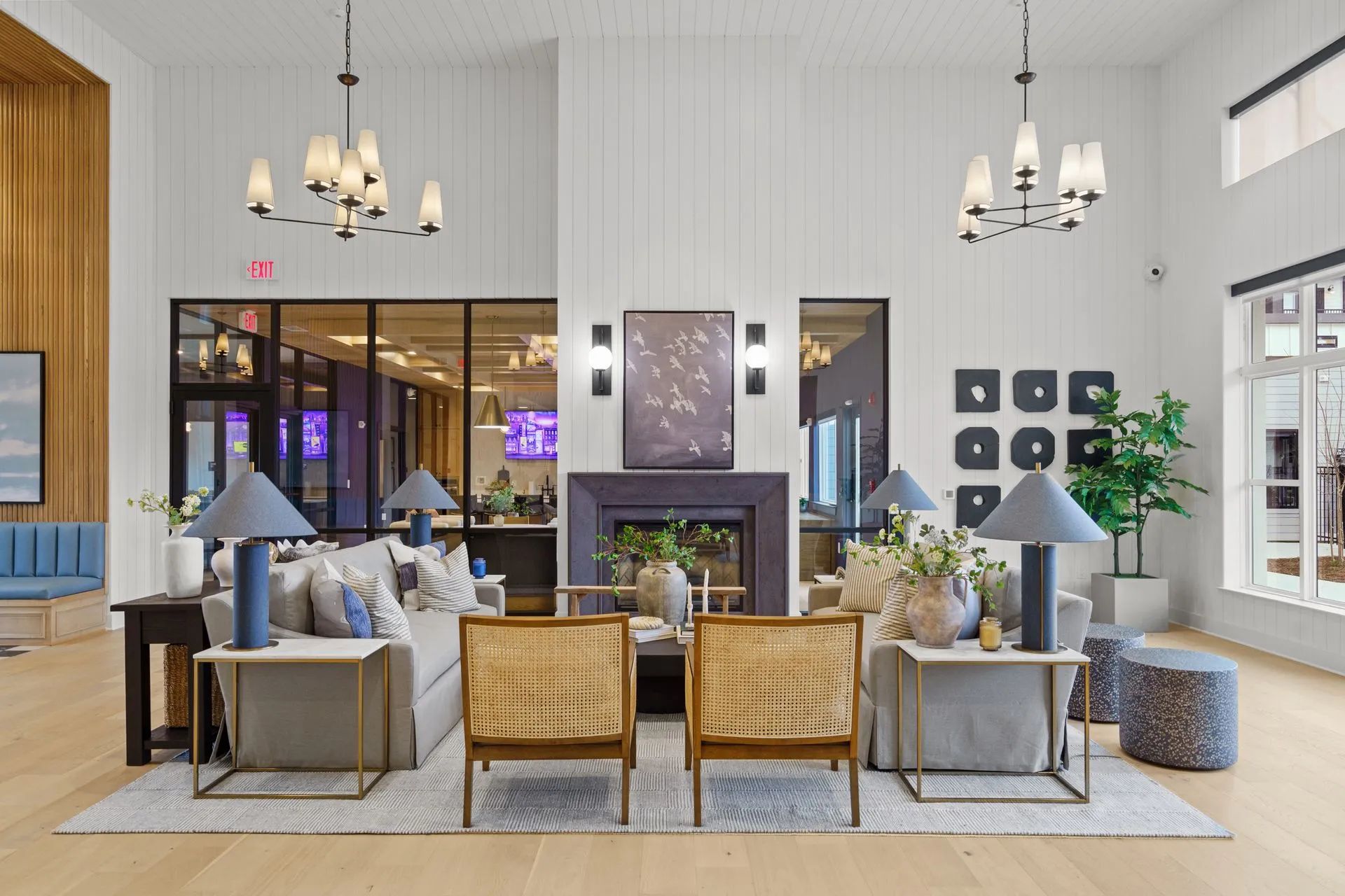 Lobby with seating areas, fireplace, and chandeliers. Light wood floors, white walls, and glass panels.
