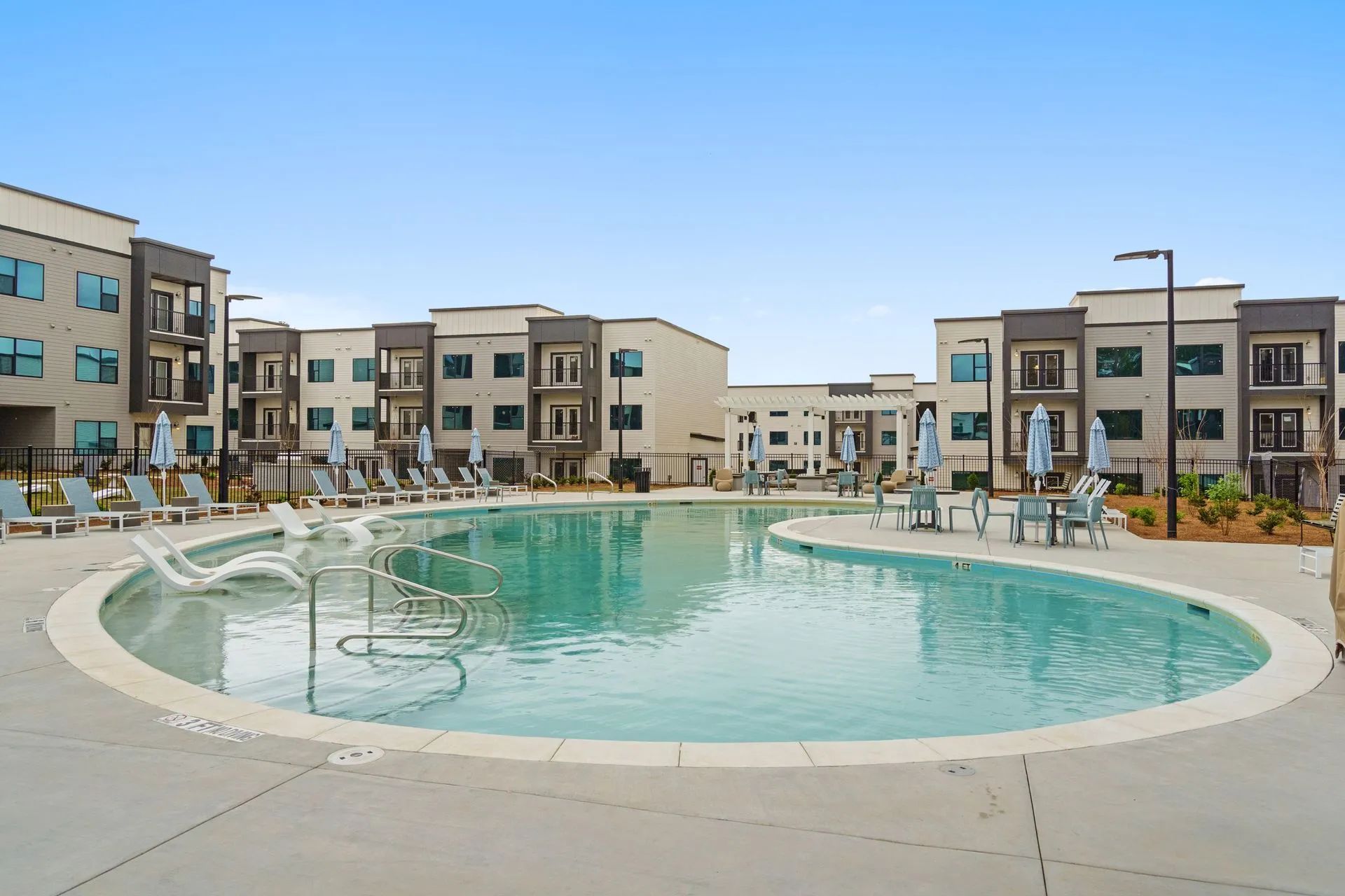 Swimming pool surrounded by apartment buildings under a clear blue sky.