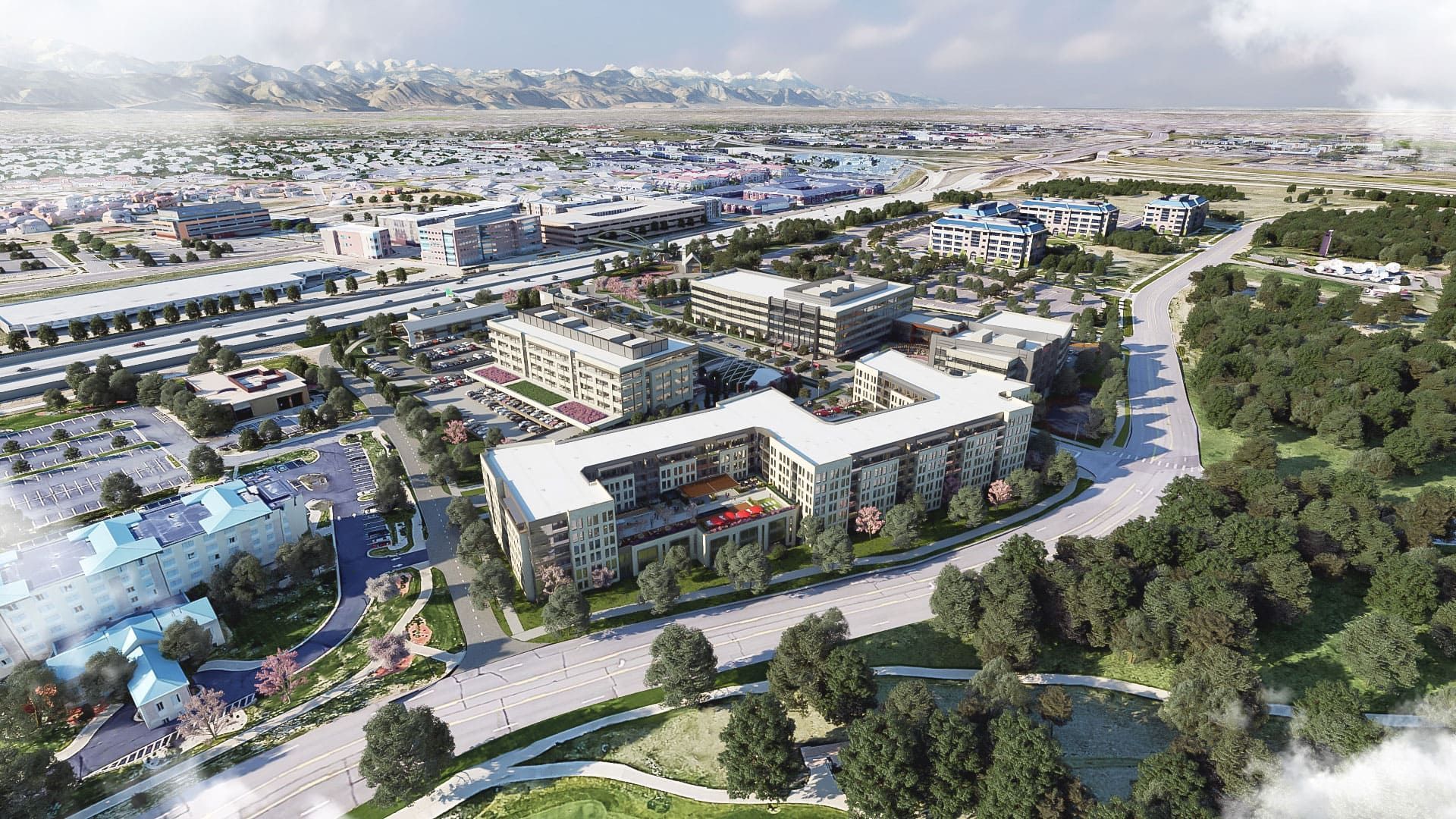 Aerial view of modern buildings and park with mountains in the background.