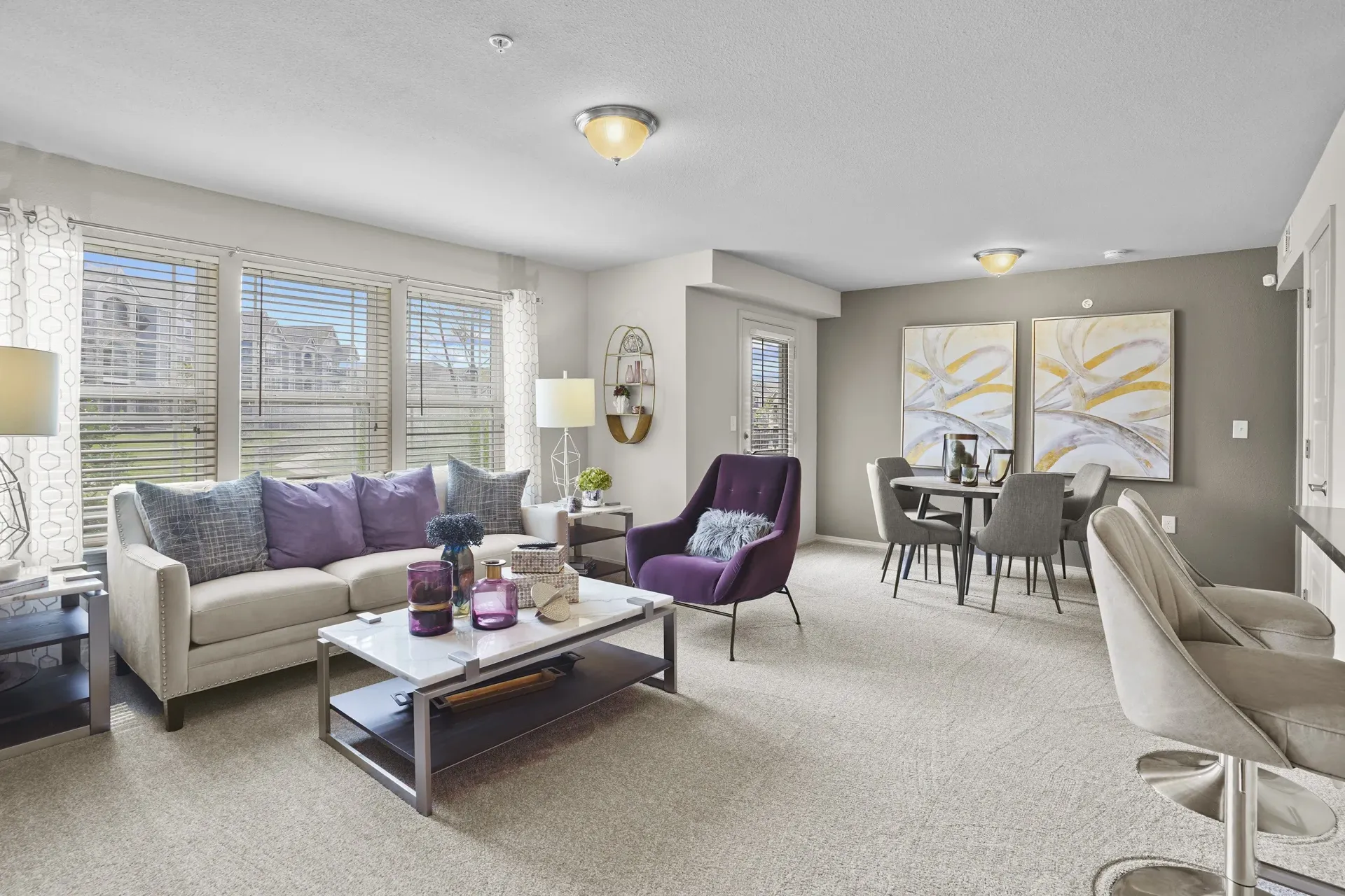 A living room with a purple chair and a grey couch.