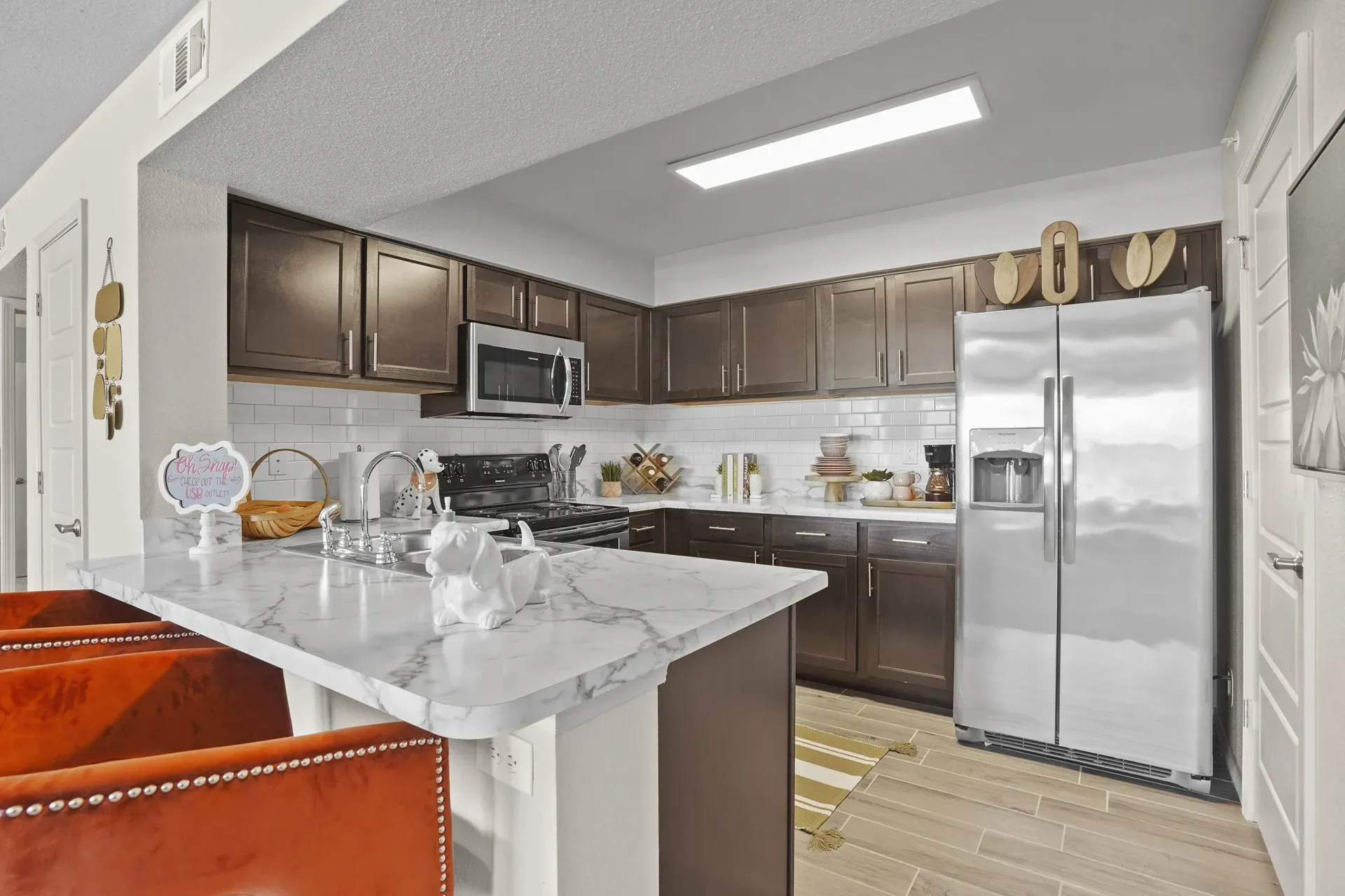 A kitchen with a white marble island and brown cabinets.
