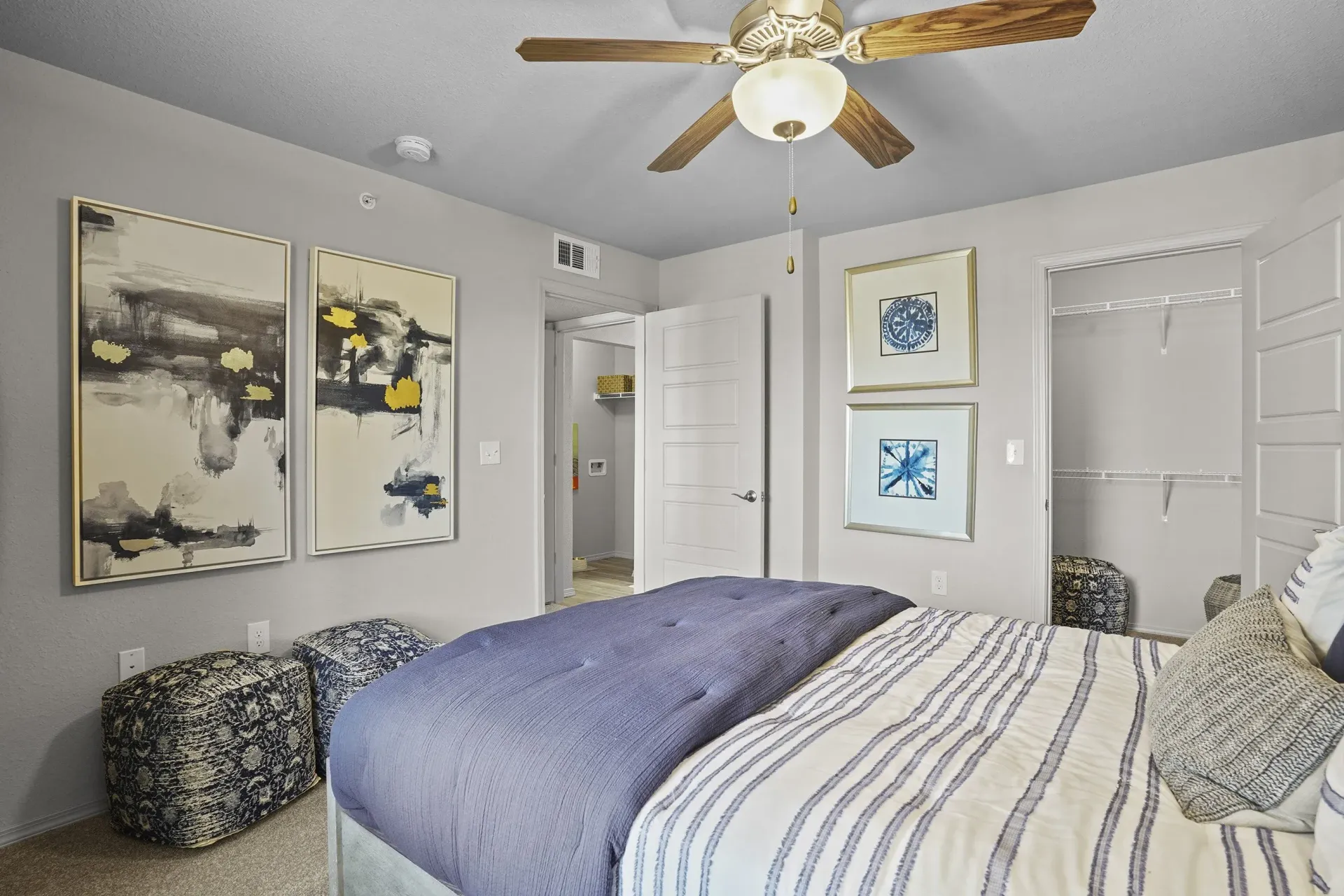 A bedroom with a bed, pillows, and pictures on the wall.