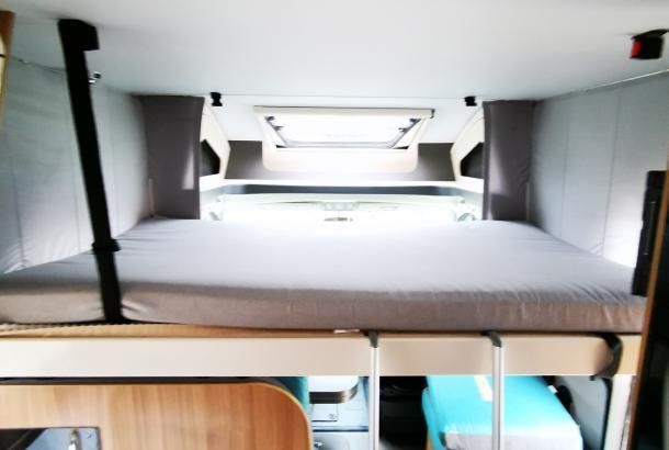 A bunk bed in the ceiling of a camper van