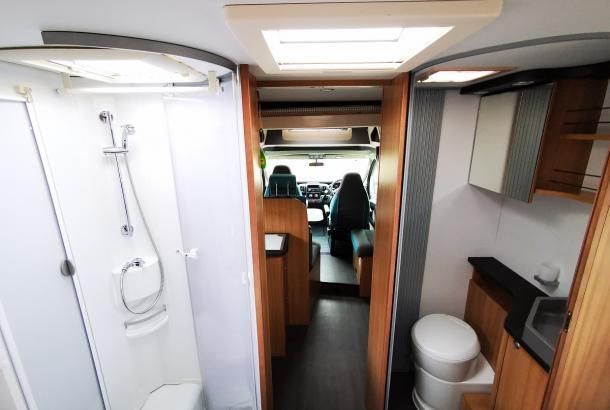 A bathroom in a camper van with a toilet and shower.