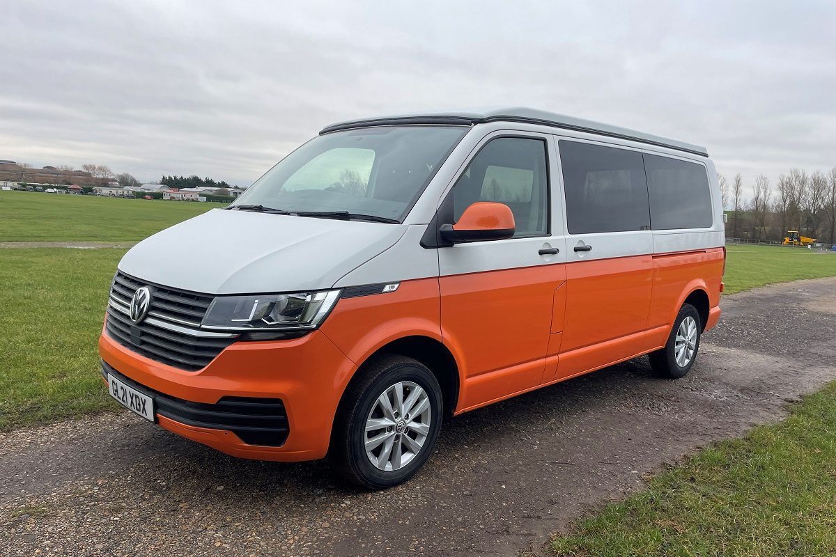 A white and orange van is parked on the side of a road.