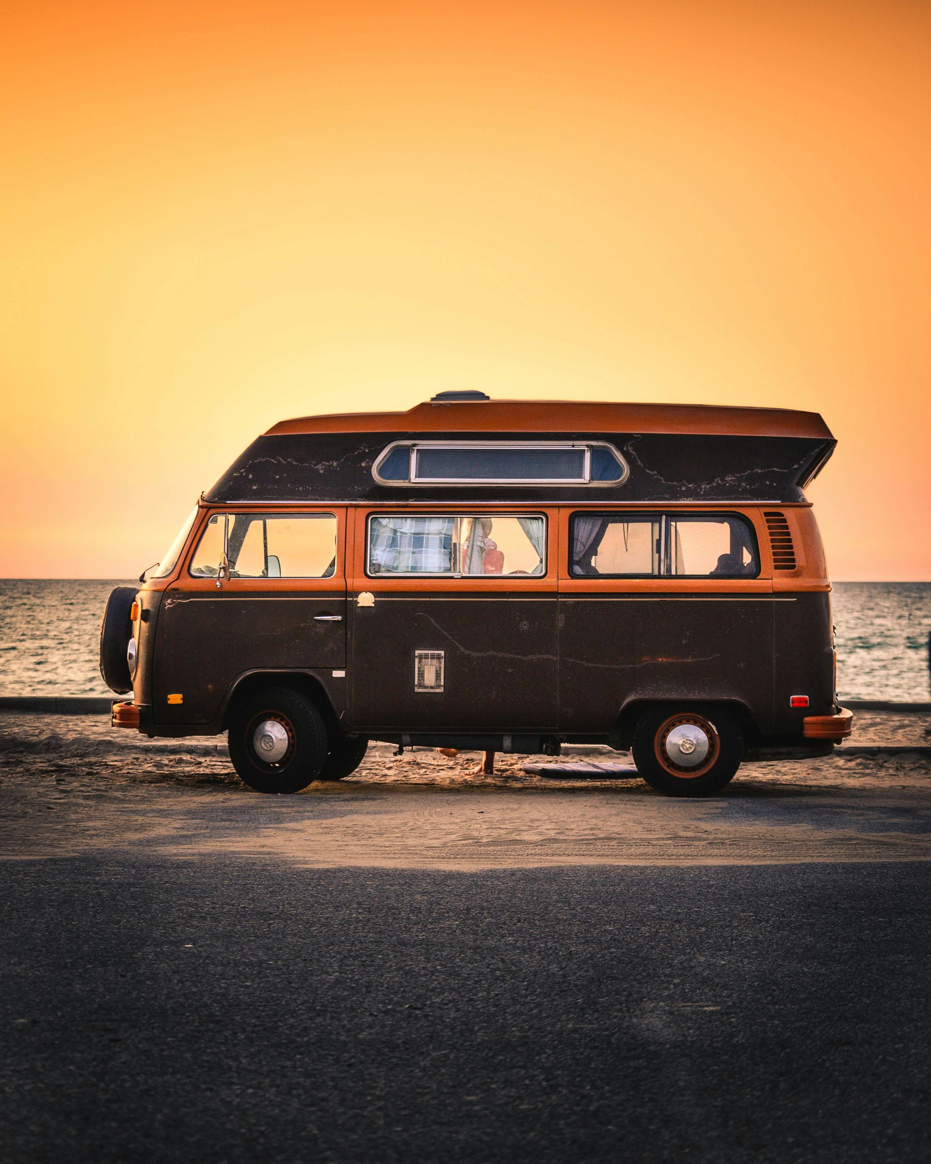 A camper van is parked on the side of the road near the ocean.