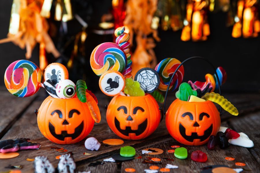 Colorful Halloween candy in little smiling pumpkin baskets