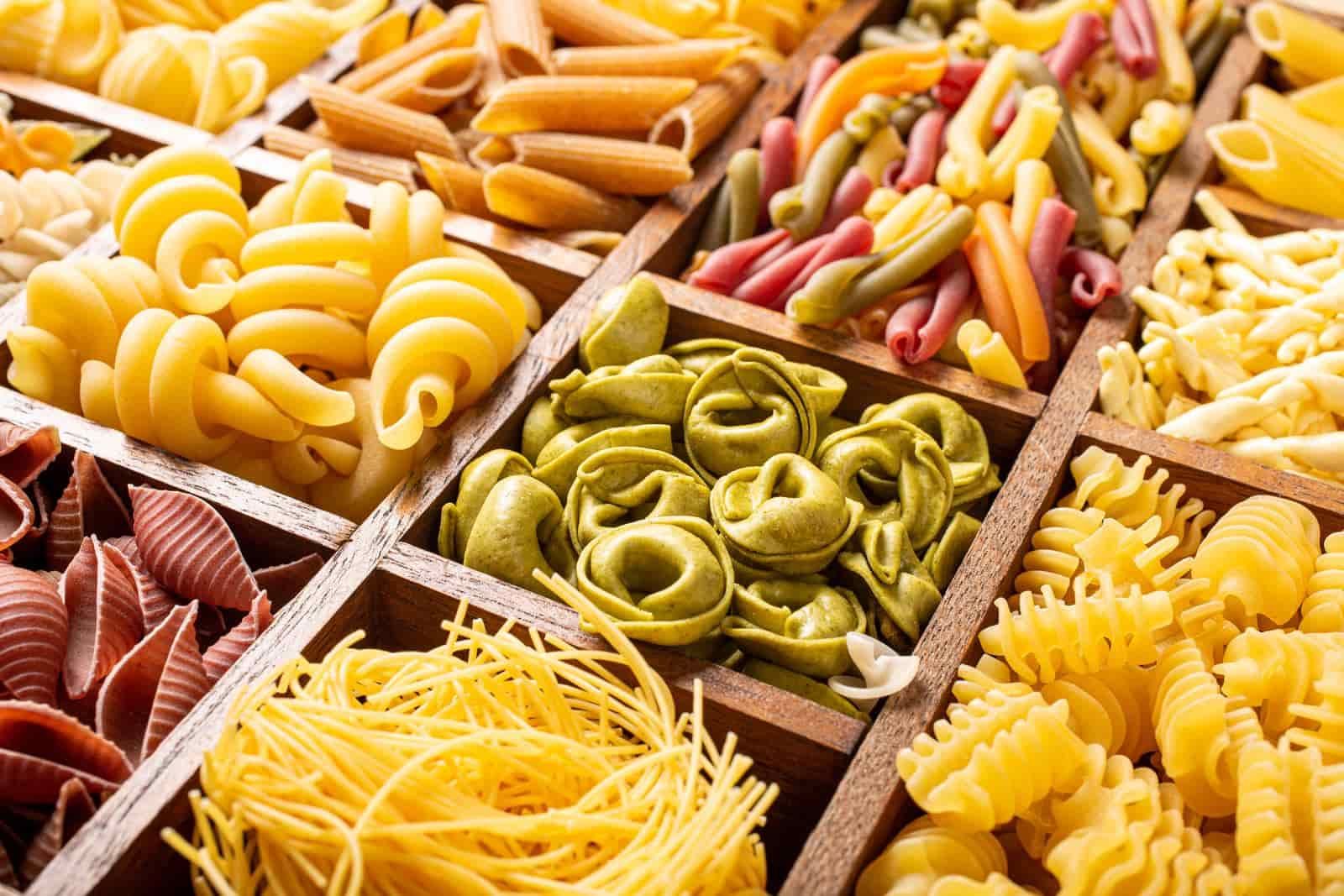 Spaghetti and assorted colorful italian pasta in wooden box. 
