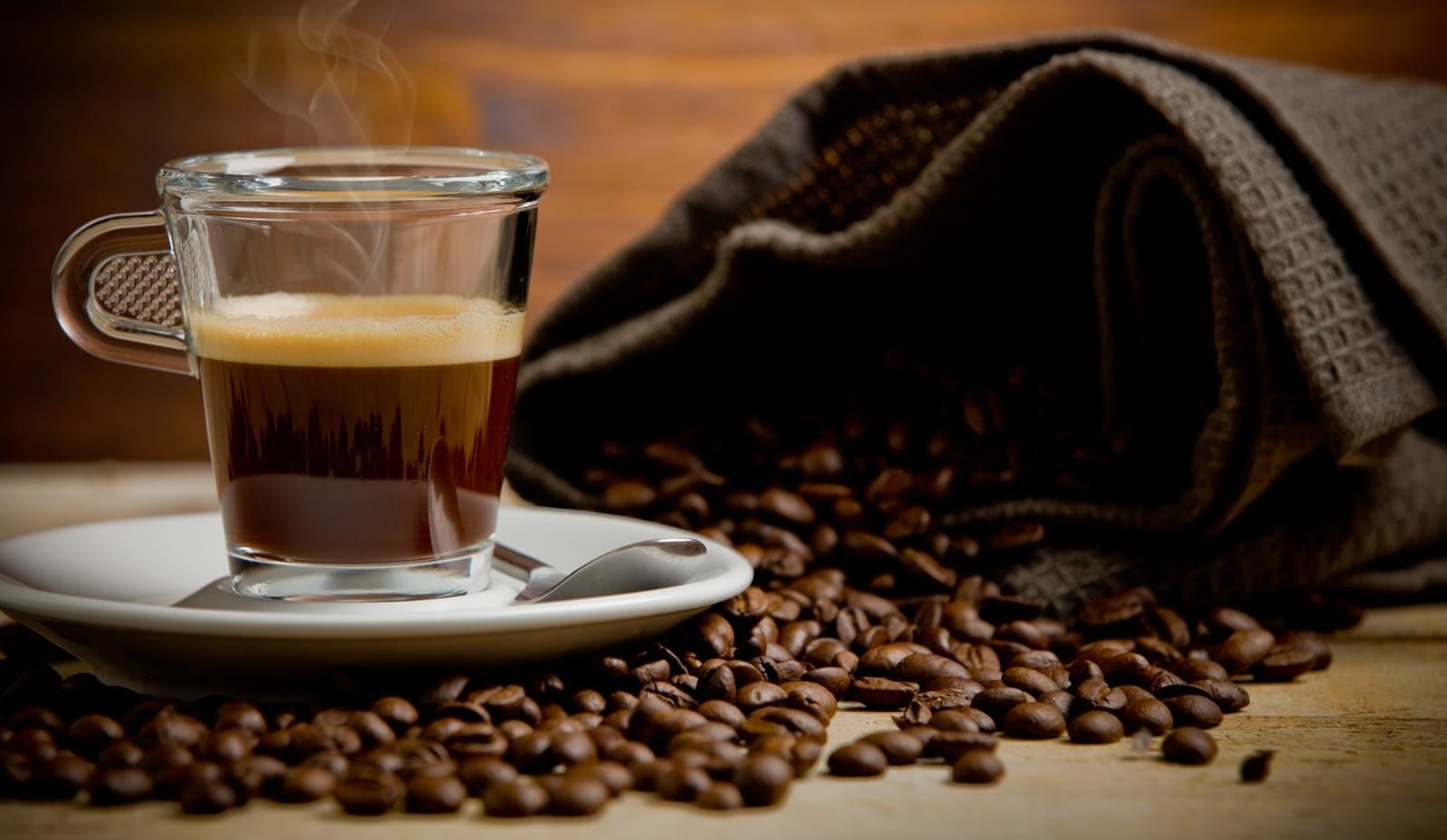 hot smoking coffee inside glass cup on wooden table