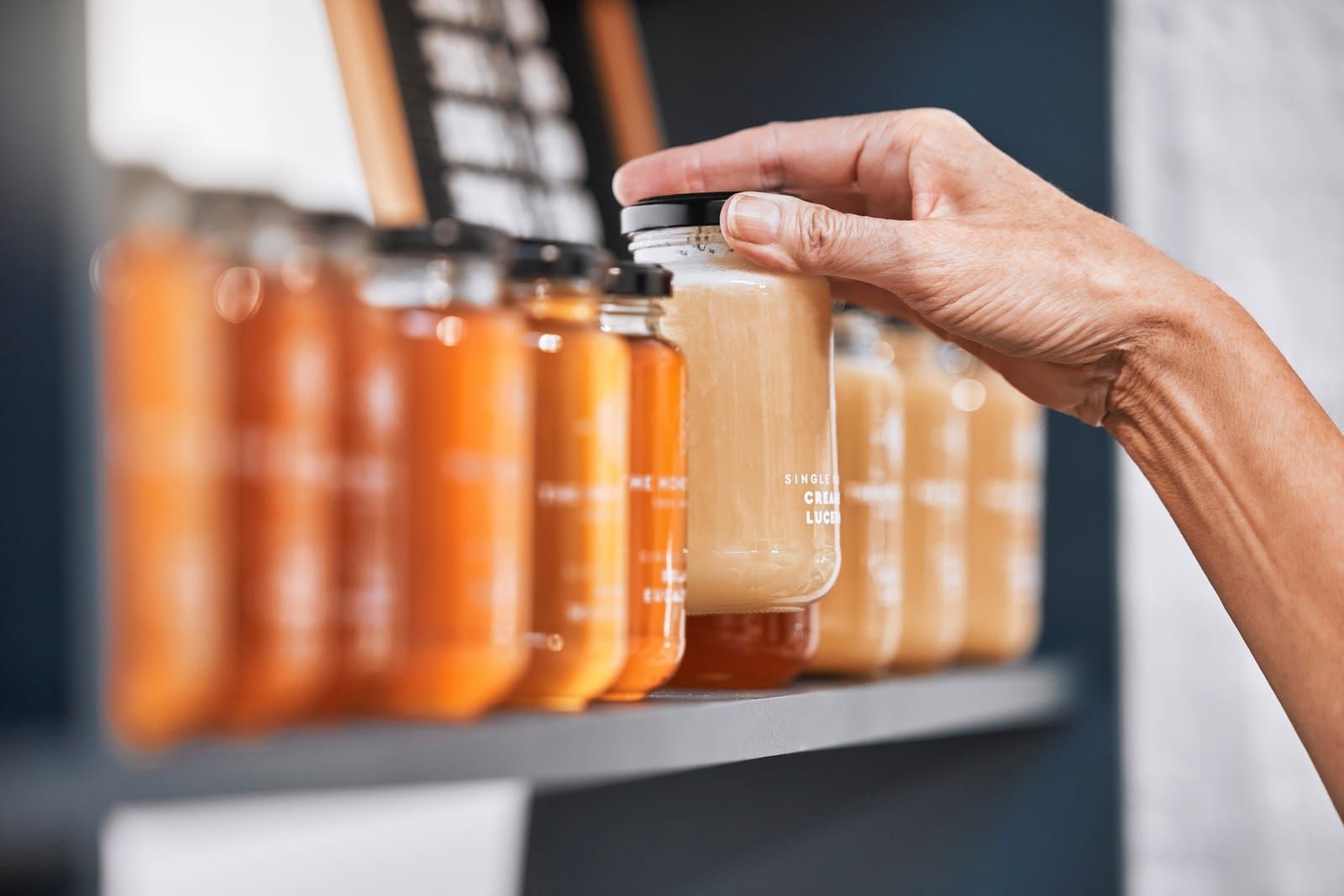 Jars with food on a shelf and a hand holding one