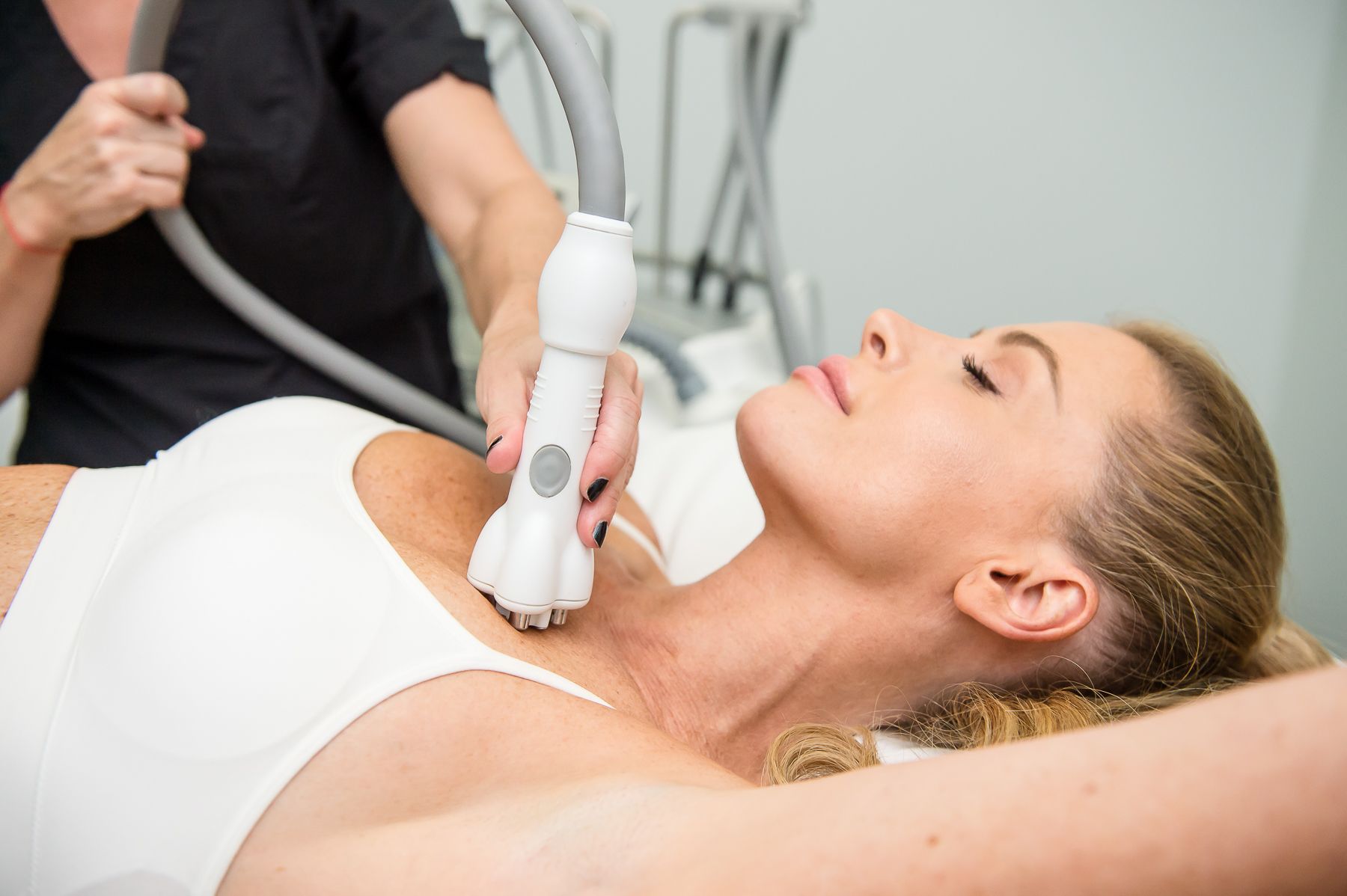 Woman receiving neck treatment with a handheld device.