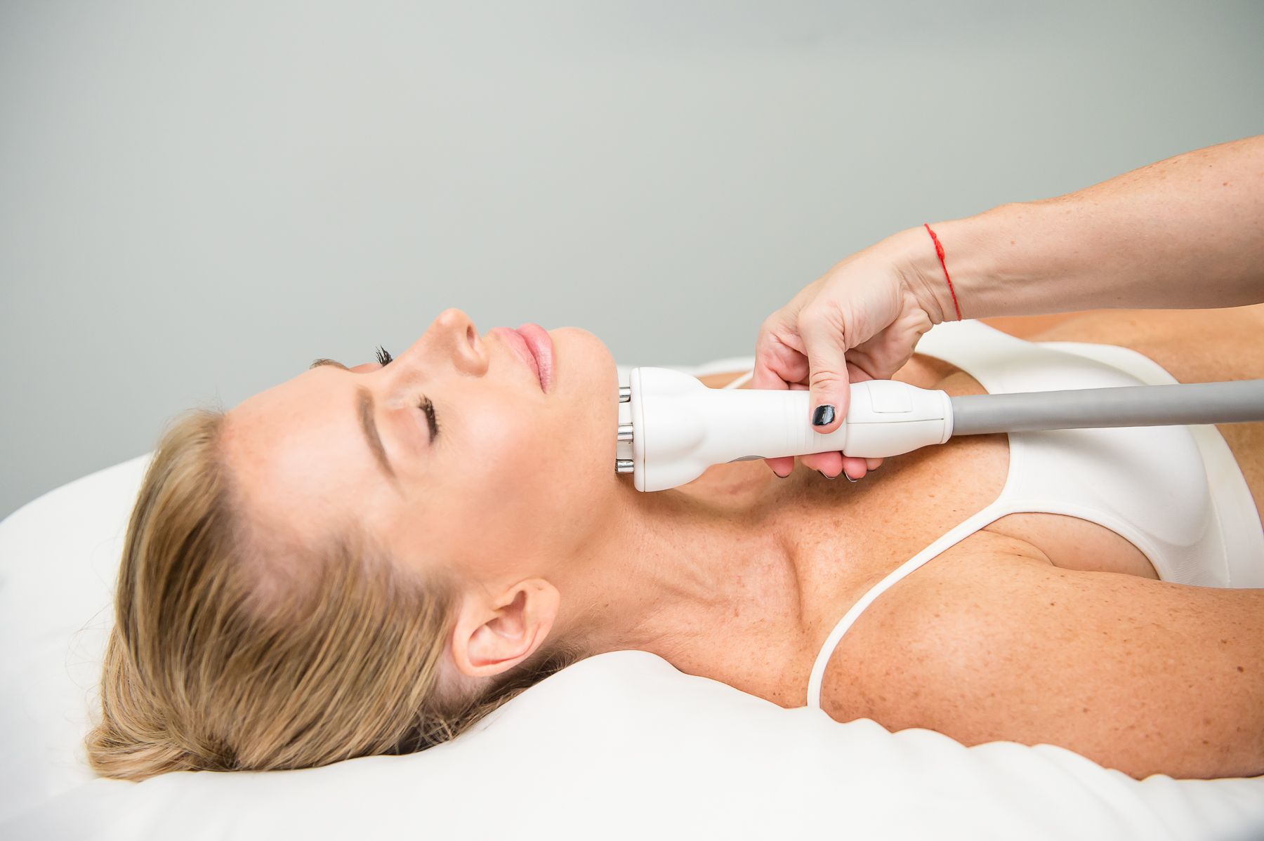 Woman receiving neck treatment with a handheld device in a spa setting.