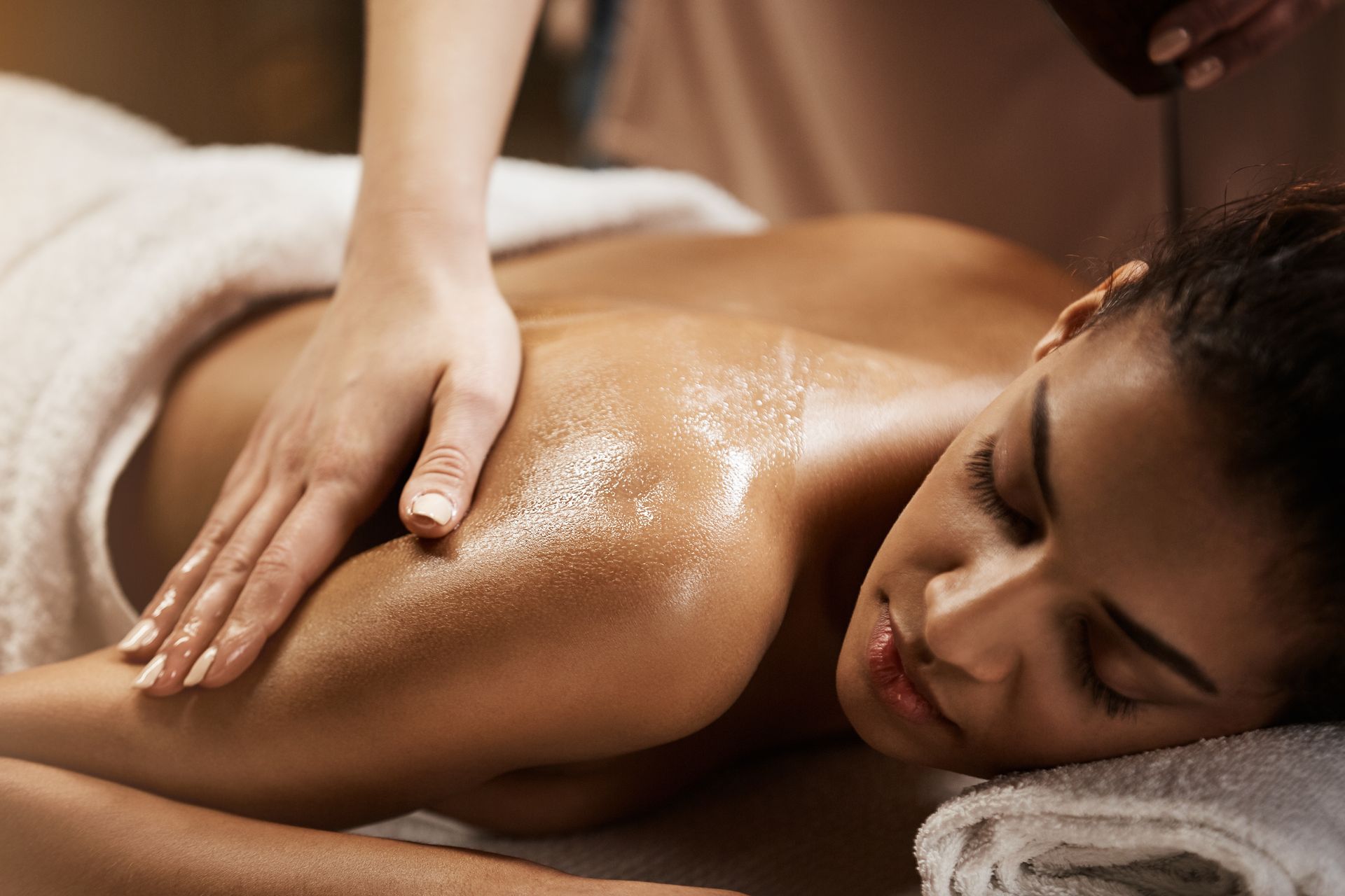 Woman receiving a back massage in a spa setting with oil applied.