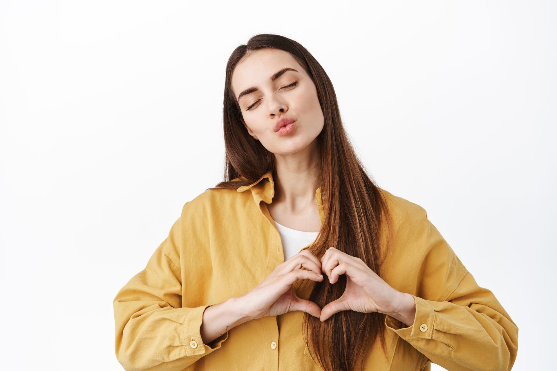Woman in black dress making a heart shape with her hands and kissing toward the camera.
