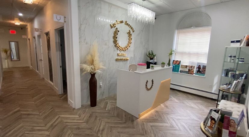 Lobby with white reception desk, marble wall, hallway with doors, and products on shelves.