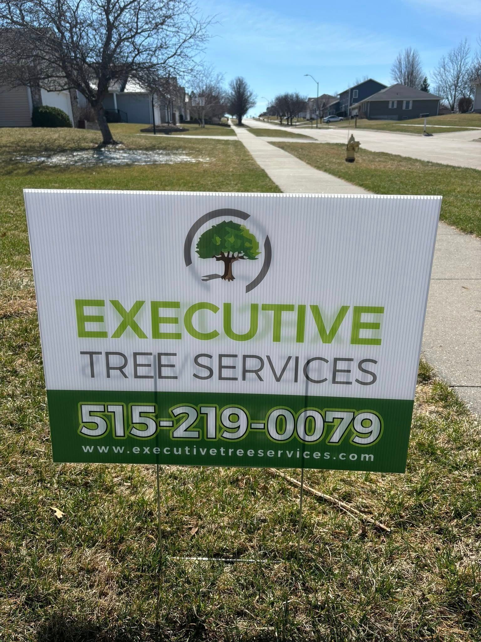A sign for executive tree services is sitting in the grass.