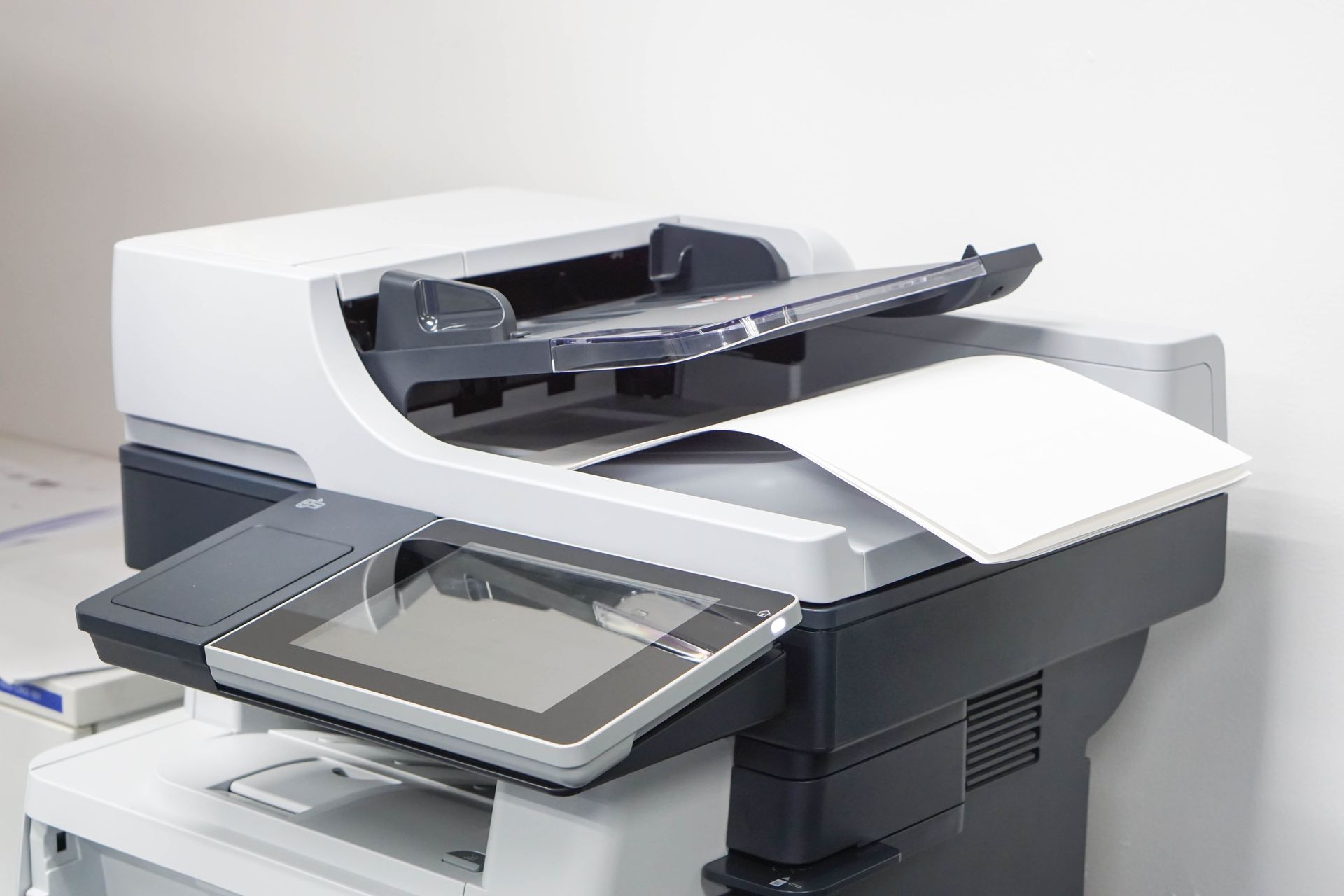 A white and dark gray office printer with an automatic document feeder and a touchscreen control panel.
