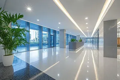 Modern office lobby with glossy white floor, large windows, and potted plants.