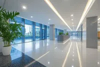 Modern office lobby with glossy white floor, large windows, and potted plants.