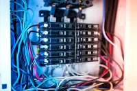 Electrical panel with blue, black, and white wires connected to circuit breakers.
