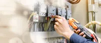 Electrician using a multimeter to test wiring in an electrical panel.