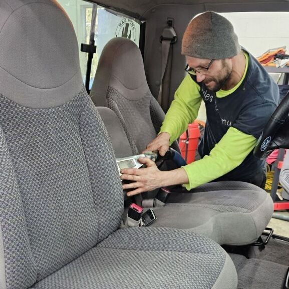 A man is working on the back seat of a car